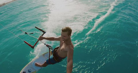 Young athletic man kitesurfing POV in slow motion at sunset, extreme sports POV, tropical island surf adventure