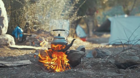 Large Kettle Over a Camp Fire in Front of Tents at a Refugee Camp.