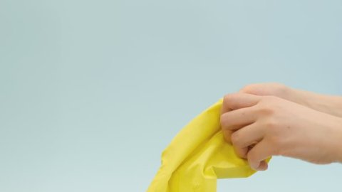 people, housework and housekeeping concept - woman putting on rubber gloves for housework at home. skin safety when working with household chemicals