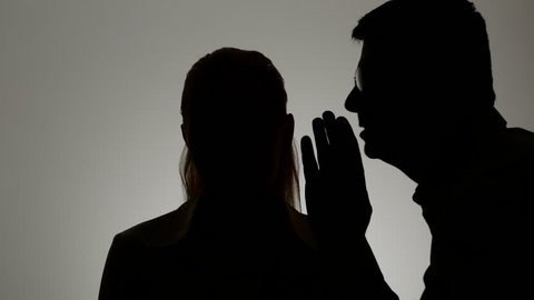 Silhouette of a man and a woman. A man whispers in a woman's ear.