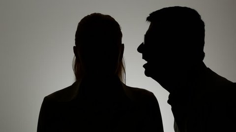 Silhouette of a man and a woman. A man whispers in a woman's ear.