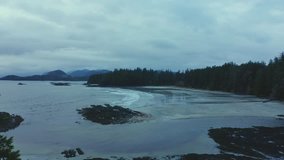 Early morning drone flight along a secluded Pacific North West beach, with mountains in the background.