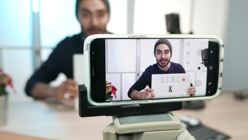 vlogger filming a video of himself asking to the viewers to like and subscribe to his channel on social media.