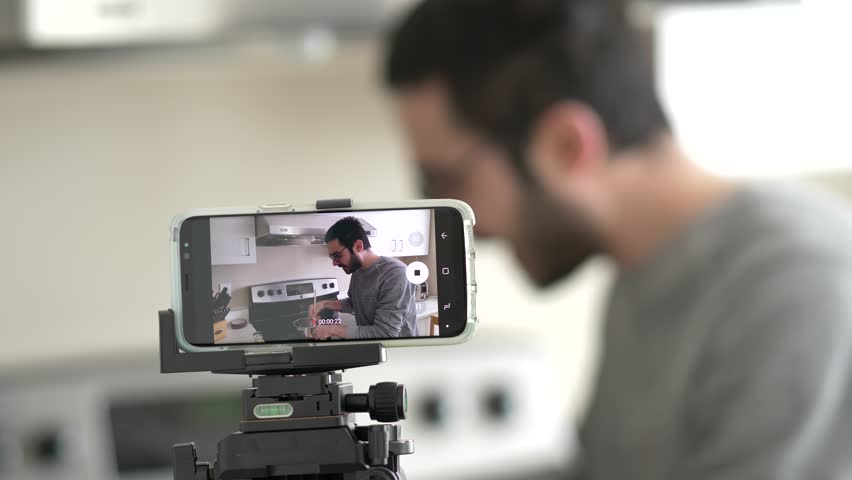 Cooking blogger filming a video of himself to post it on social media to be viewed by many viewers. | Shutterstock HD Video #1028200352