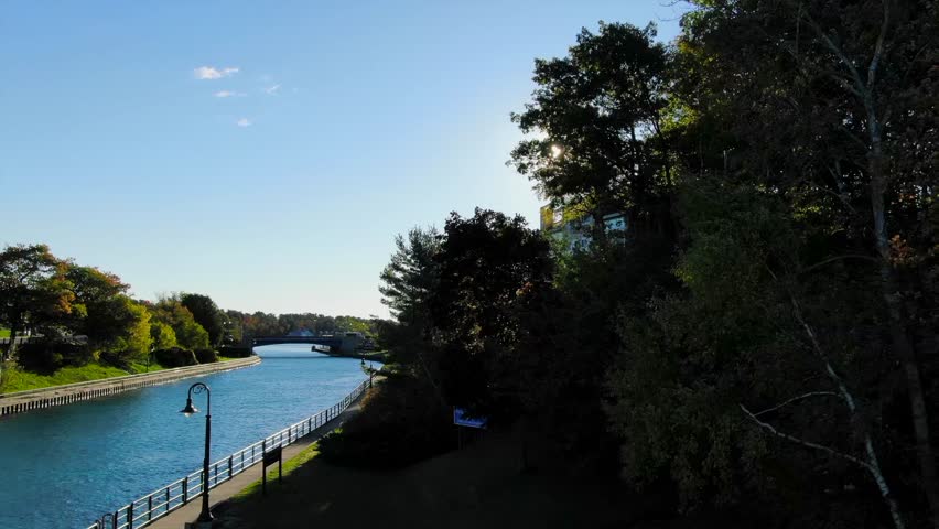 Warm Fall Day Charlevoix Northern Michigan sun bursting through Trees bridge and river Lake Michigan.