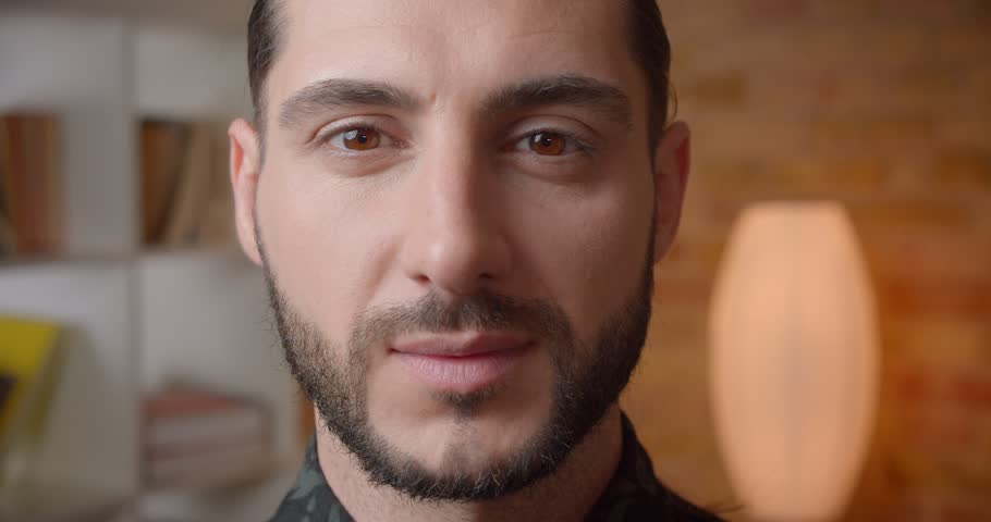 Closeup shoot of young attractive muslim bearded male face looking at camera indoors
