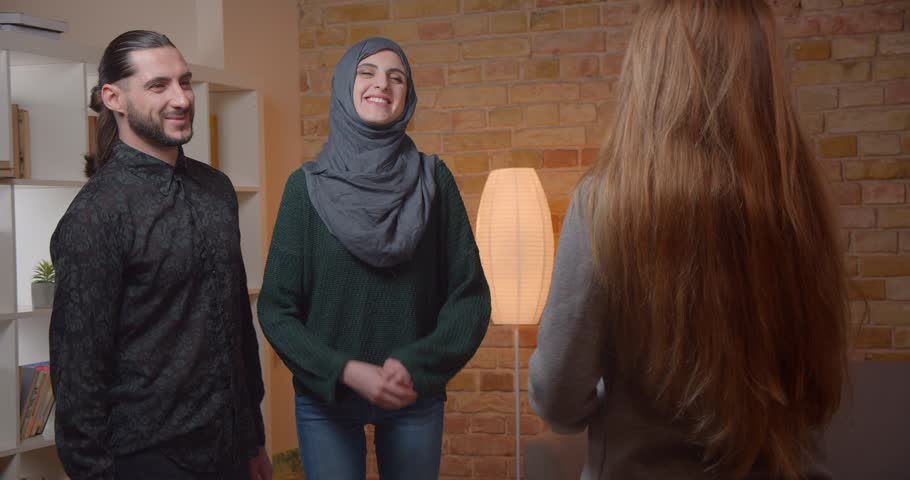 Closeup shoot of young attractive muslim coulpe buying an apartment receiving keys from realter smiling and hugging happily