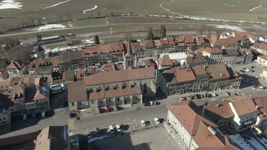 Wide aerial shot circling around an old medieval church in Romont Switzerland.