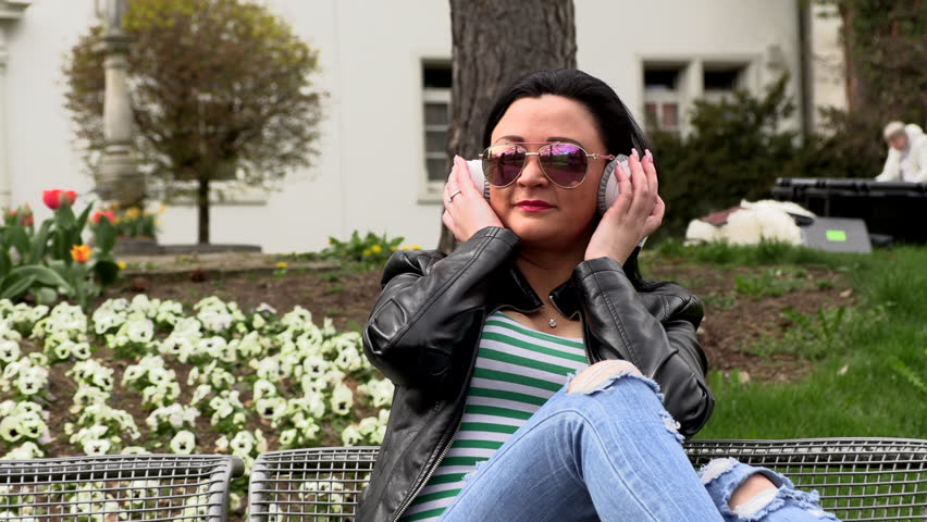 Brunette sits on a street bench and listens to music