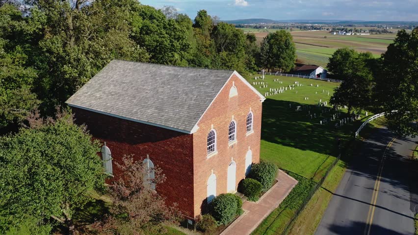 Colonial church with cemetery from the revolutionary war in background, aerial dolly shot of small town Brickerville in Pennsylvania