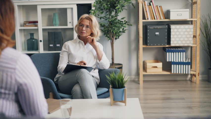 Experienced female psychologist is talking to emotional obese woman who is speaking and gesturing sharing problems in office. Psychological help and people concept. | Shutterstock HD Video #1028214146