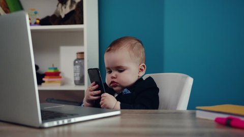 Child businessman boss boy in office use laptop phone sitting play creative little happy job kid work child computer education young suit cute career confident slow motion