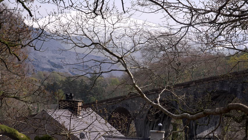Train going up mountain and over bridge in Snowdon Wales UK. Tourist rout to the top of mountains 4K