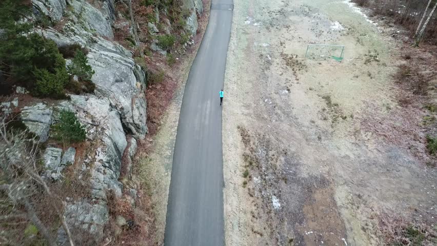 Arial drone view of a guy running on a road