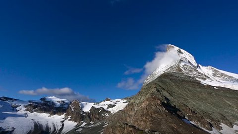 Panoramic footage of North east view of the Matterhorn peak and area during sunrise in sunny day with deep blue sky. Matterhorn (peak Cervino) in Swiss Alps. Beautiful natural landscape in the