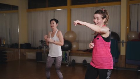 Two women doing exercise in the aerobic room with the use of the balance board.