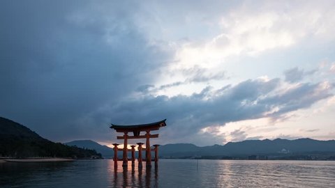 TIME LAPSE: Beautiful sunset on the Floating Torii gate with high tide and touristic boat. Miyajima, Japan.