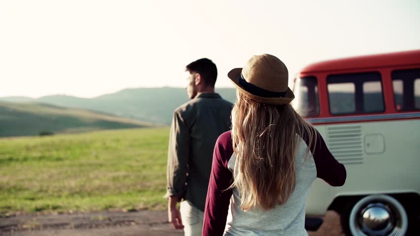 Young couple on a roadtrip through countryside, walking. Slow motion.