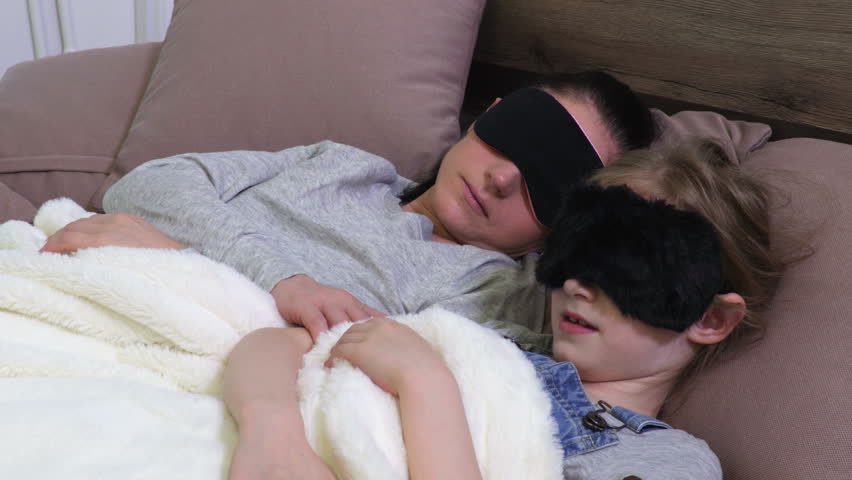 Mother and daughter in sleeping masks in bed