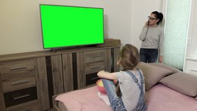 Daughter and mother near TV with green screen
