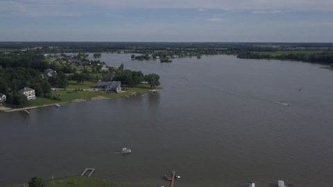 Aerial drone footage of boaters on a Michigan lake during a sunny summer day. Lake Houses and docks visible on the shore