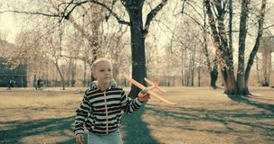 Happy traveler boy playing with airplane toy on sunny day in park. 4K slow motion video. Child runs on mountain at sunset.