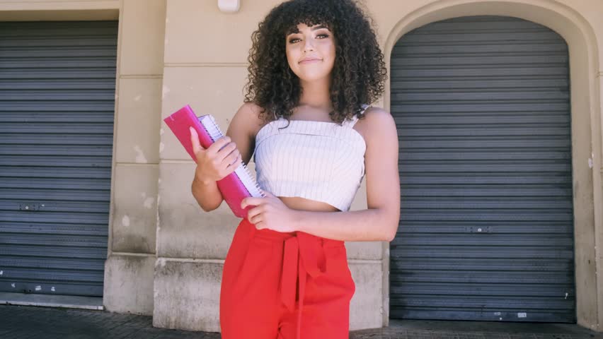 Female student in campus with books in her arms. 4K. Premium cinematic video.