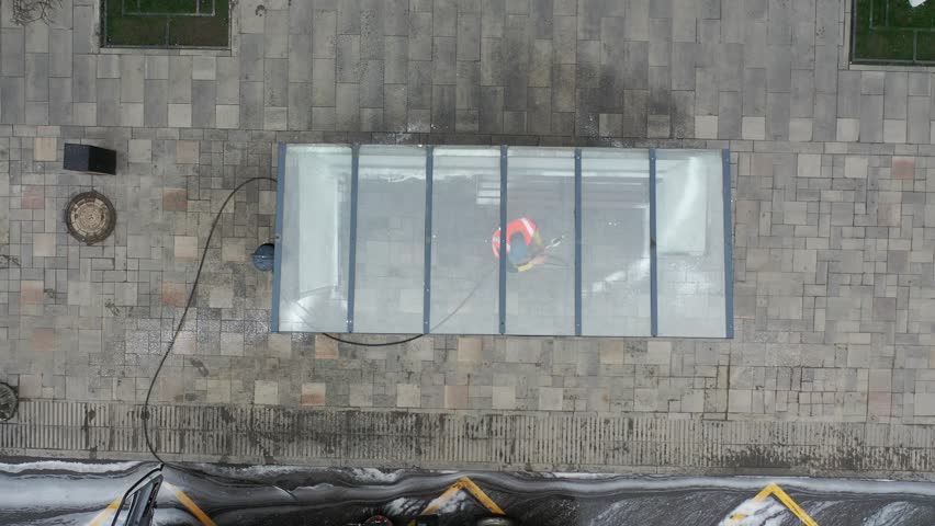 Cleaning bus station via municipal services. Text on the car - name of the city district - Leninskii district