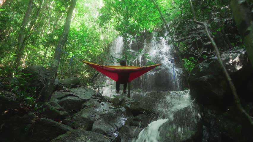 A man swaying on a hammock while enjoying the beauty of nature