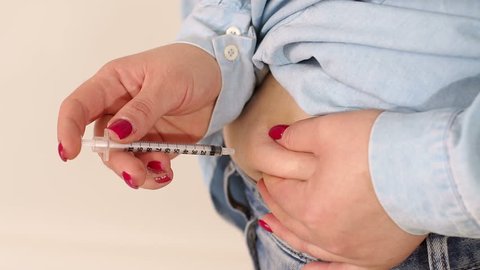 Close-up of a woman makes a shot of insulin in the fat fold on the stomach. Treatment of type 1 diabetes. Theme diabetes. Slow motion.