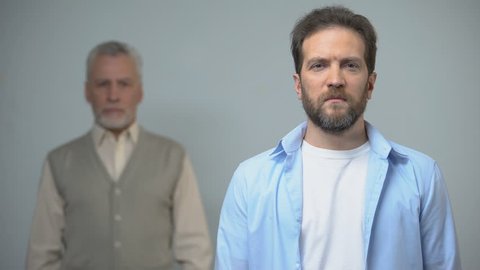 Adult male looking at camera, senior man standing behind, pensioner care program