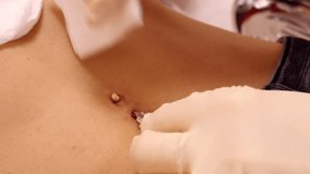 slow motion closeup piercing master in gloves wipes skin with cotton napkin around gold sparkling belly button ring  - Powered by Shutterstock - Get 15% off with code: PIKWIZARD15