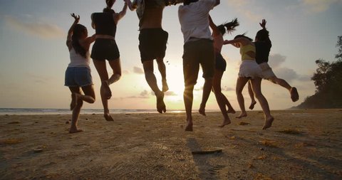 SLOW MOTION - Group of friends running on the beach at sunset with happy emotion. People with party celebration concept. Back Rear View.