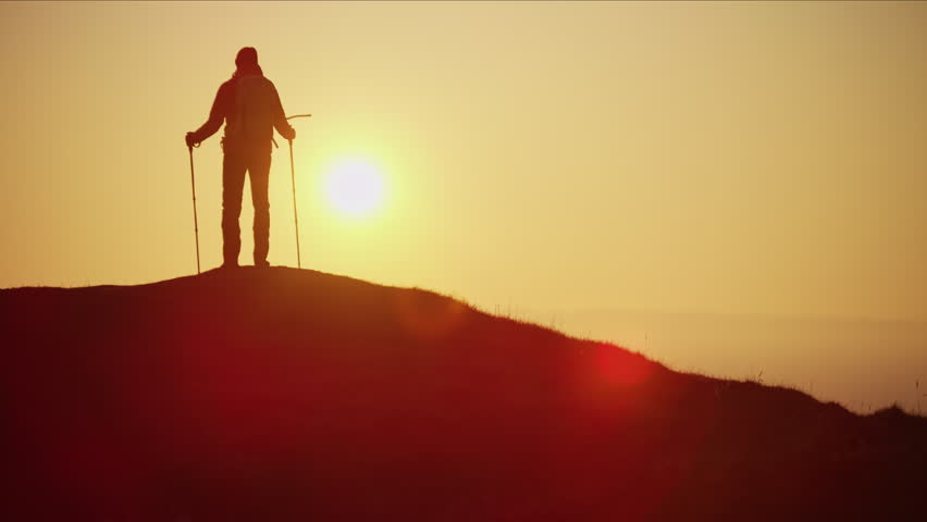 Silhouette of fit Caucasian European female hiker with rucksack achieving her ambitions trekking at sunset Snowdonia Wales RED MONSTRO