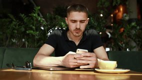 Video man using phone in a cafe