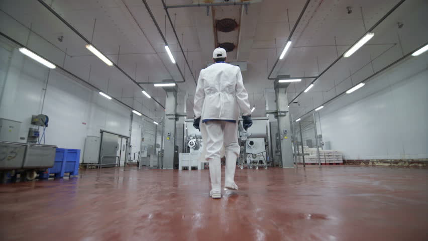 Follow footage of factory worker in cap that is walking through industrial facilities in meat plant. Sausage production Royalty-Free Stock Footage #1028327543