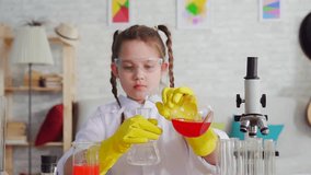 girl teen blogger in a white coat and glasses in the laboratory ,mixes the reagents