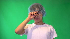 The girl plays a role-playing game. Conduct research. Looks through a magnifying glass. White shirt. On anybody protective cap. Green background. 4K video