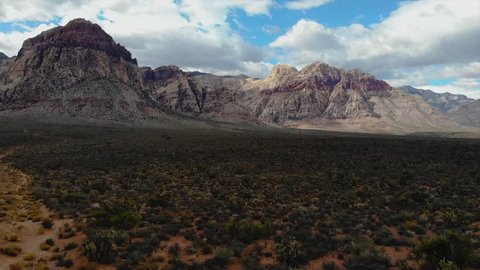 4K resolution, aerial drone at 24 frames per second over mountain in Red Rock Canyon National Park and Desert outside Las Vegas, Nevada with cloudy skies (speed ramping / fast forward / sped up)