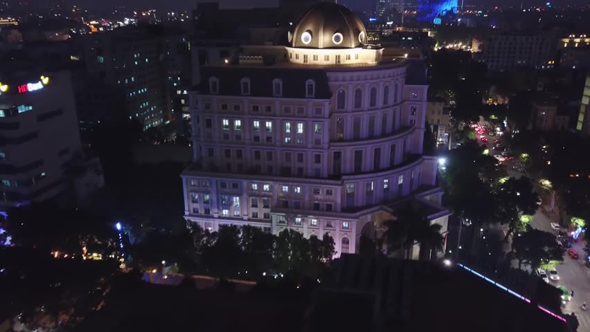 Aerial near forward dome french colonial style building City center Capital of Vietnam Hanoi. Night illumination neon. Modern city development in background. Tourism journey. Traffic jam. Night life. 