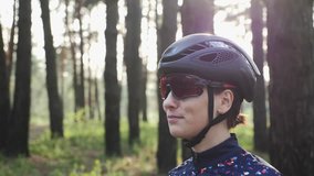Woman cycling. Girl bicycle training. Portrait of happy triathlete girl putting off cycling glasses wearing black helmet. Cycling concept