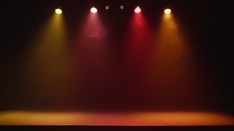 The stage of a small theater with colorful spotlights flashing on and off.
Lights are turned on from darkness.