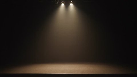 The stage of a small theater with white spotlights.
Lights are turned on from darkness.
