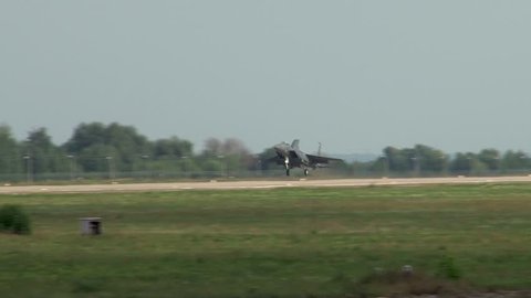 Zhukovsky, Russia, August 16, 2011. Landing of American all-weather fighter F-15 Eagle on Russian concrete runway. Dark gray plane is rolling on runway with raised nose on two main landing gear.