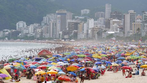 Rio de Janeiro, Brazil - December 31: Establishing shot of busy Ipanema Beach showing people and colourful sun umbrellas during summer in Rio de Janeiro, Brazil.