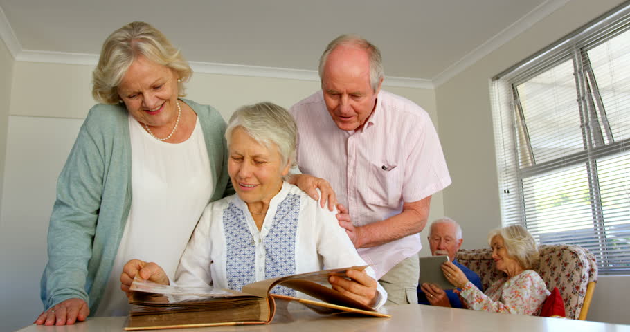 Front view of active Caucasian senior people looking at photo album in nursing home. They are interacting with each other 4k | Shutterstock HD Video #1028366561
