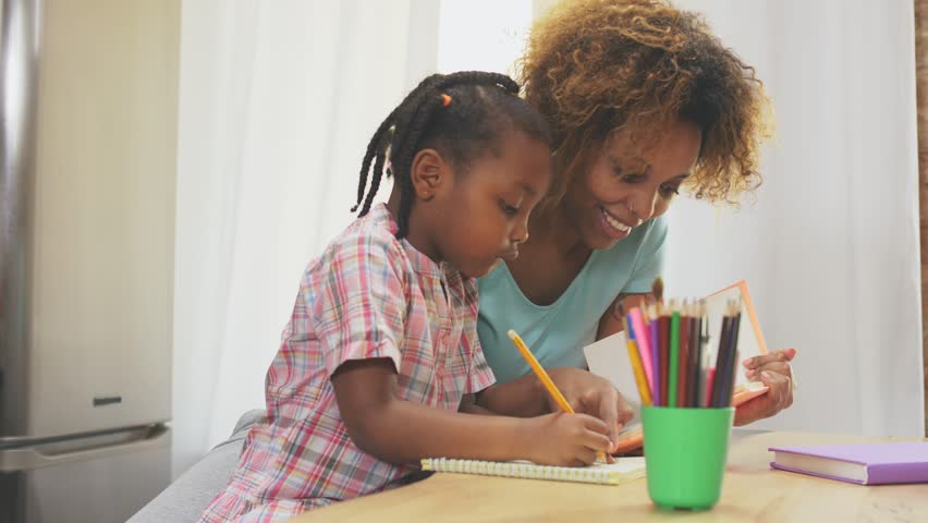 Afro-American mother and little daughter doing homework writing and reading at home Royalty-Free Stock Footage #1028372315