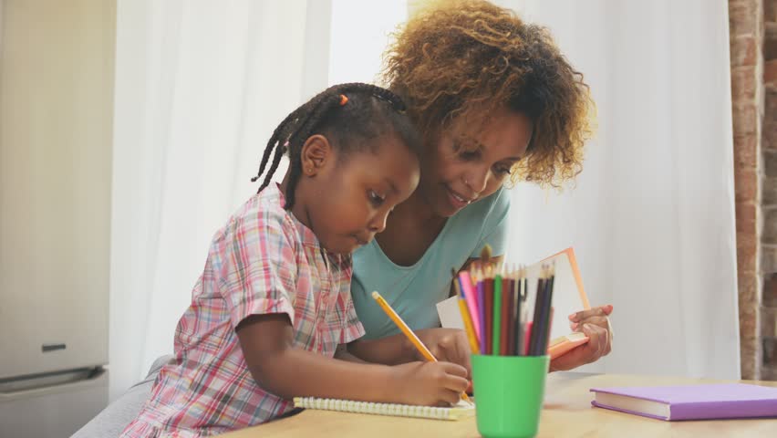 Afro-American mother and little daughter doing homework writing and reading at home Royalty-Free Stock Footage #1028372315