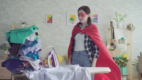 Young woman housewife superhero next to Ironing board