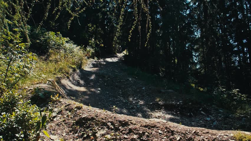 Fast downhill mountain biking on a steep trail, slow motion curve with dust